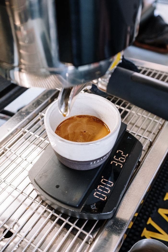 Mastering the First Impression: Your intriguing post title goes here Espresso being brewed into a cup on a digital scale in a café setting.