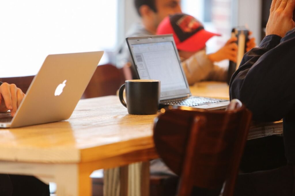 Group working in a cozy cafe with laptops and coffee mugs on a shared table.